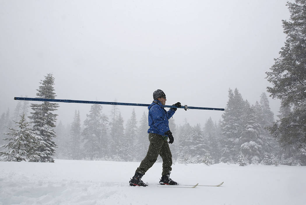 Snow falls as John King of the Department of Water Resources, crosses a meadow while conducting the third manual snow survey of the season at the Phillips Station near Echo Summit, Calif., Thursda ...
