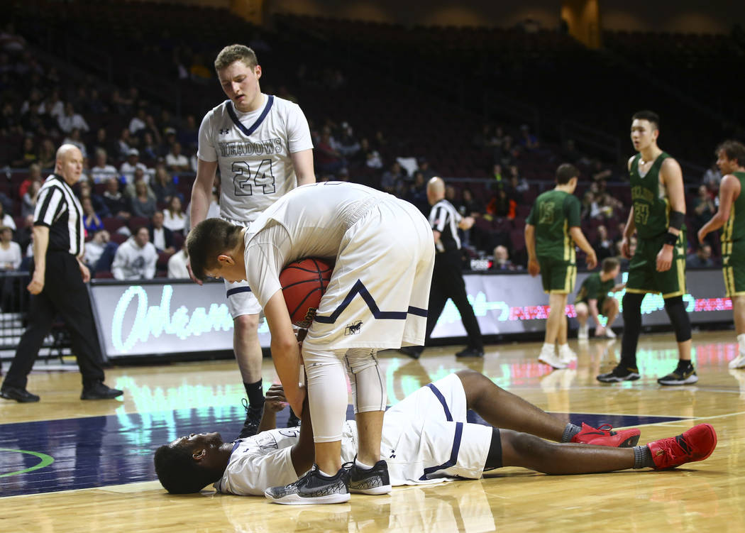 The Meadows guard Allen Fridman (24) and Trey Covell (5) check on teammate Obinna Ezeanolue during the second half of the Class 2A boys basketball state championship game against Incline at the O ...
