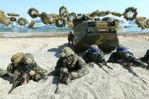 Marines of the U.S., left, and South Korea, wearing blue headbands on their helmets, take positions after landing on a beach during the joint military combined amphibious exercise, called Ssangyon ...