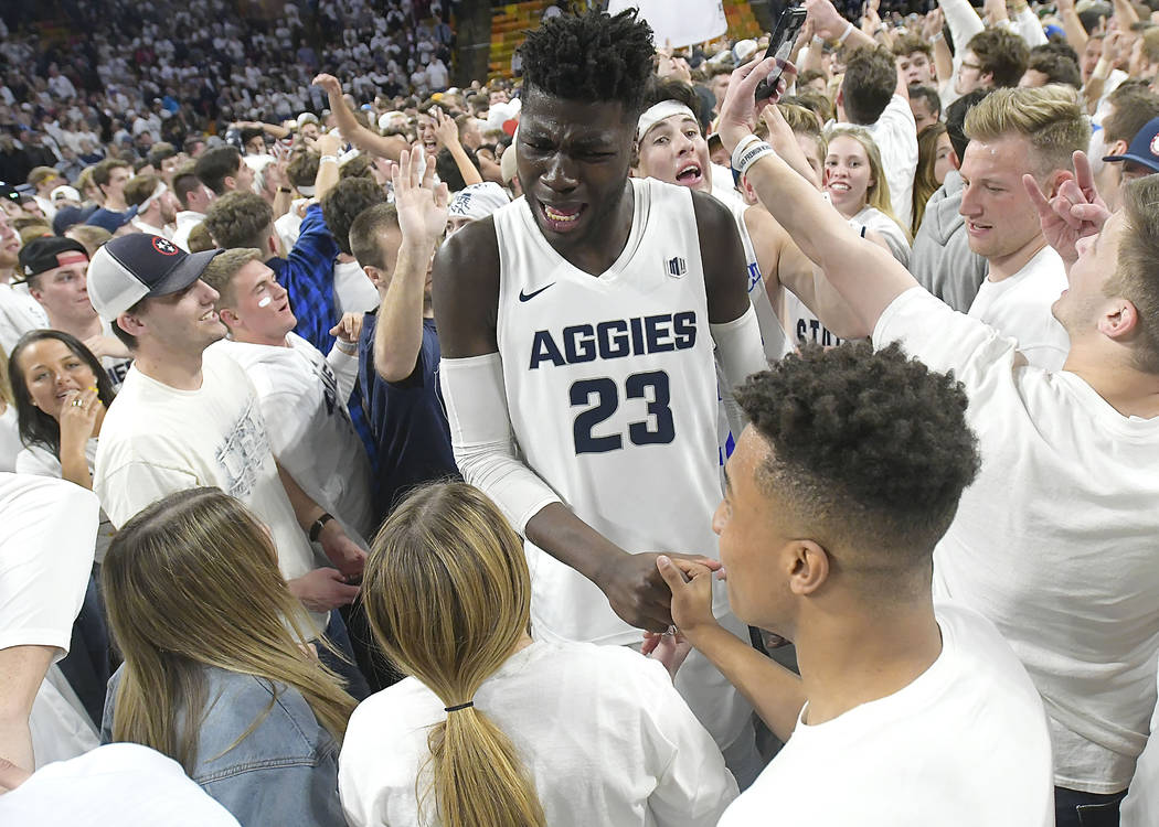 Fans celebrate with Utah State center Neemias Queta (23) on the court after Utah State defeated No. 12 Nevada 81-76 in an NCAA college basketball game Saturday, March 2, 2019, in Logan, Utah. (Eli ...