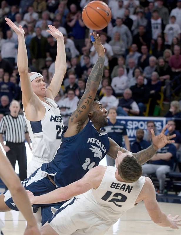 Utah State forward Justin Bean (12) draws a charge against Nevada forward Jordan Caroline (24) as Utah State guard Brock Miller helps defend during an NCAA college basketball game Saturday, March ...