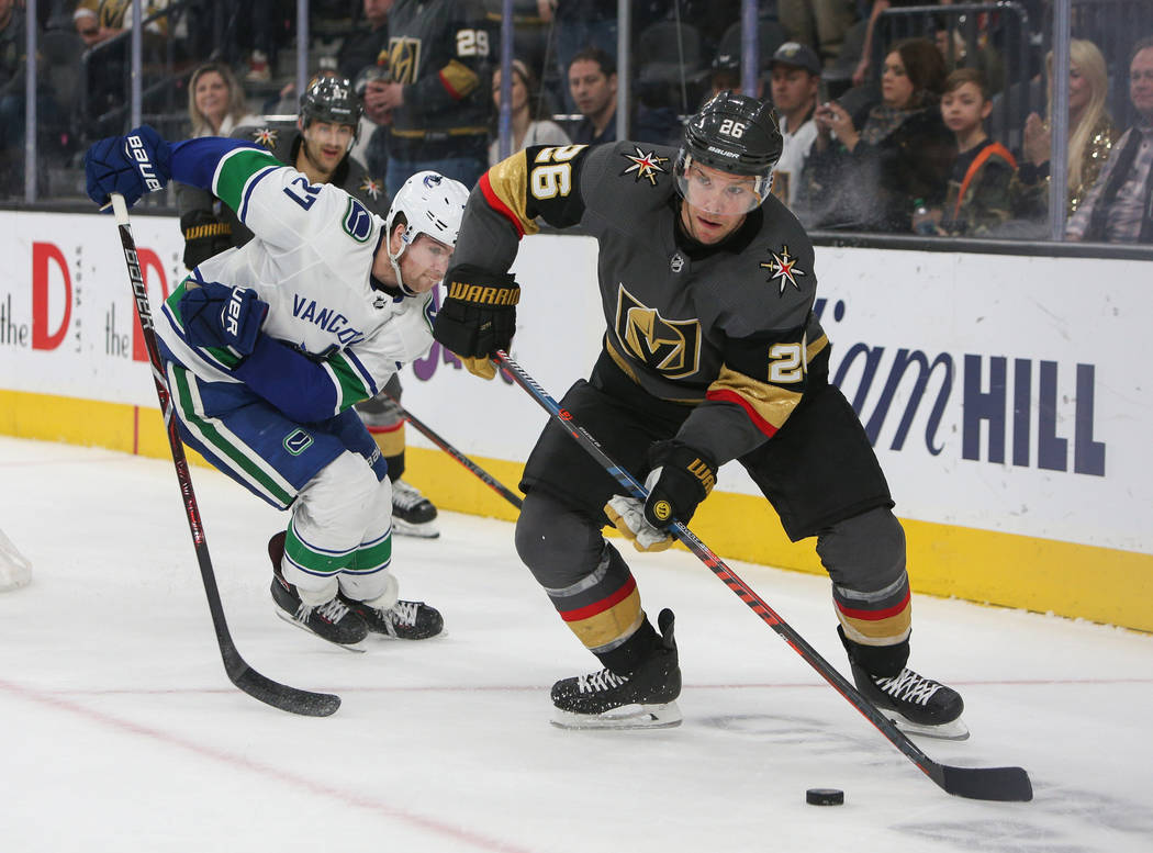 Vegas Golden Knights center Paul Stastny (26) looks to pass the puck as Vancouver Canucks defenseman Ben Hutton (27) trails behind during the third period of an NHL hockey game at T-Mobile Arena i ...