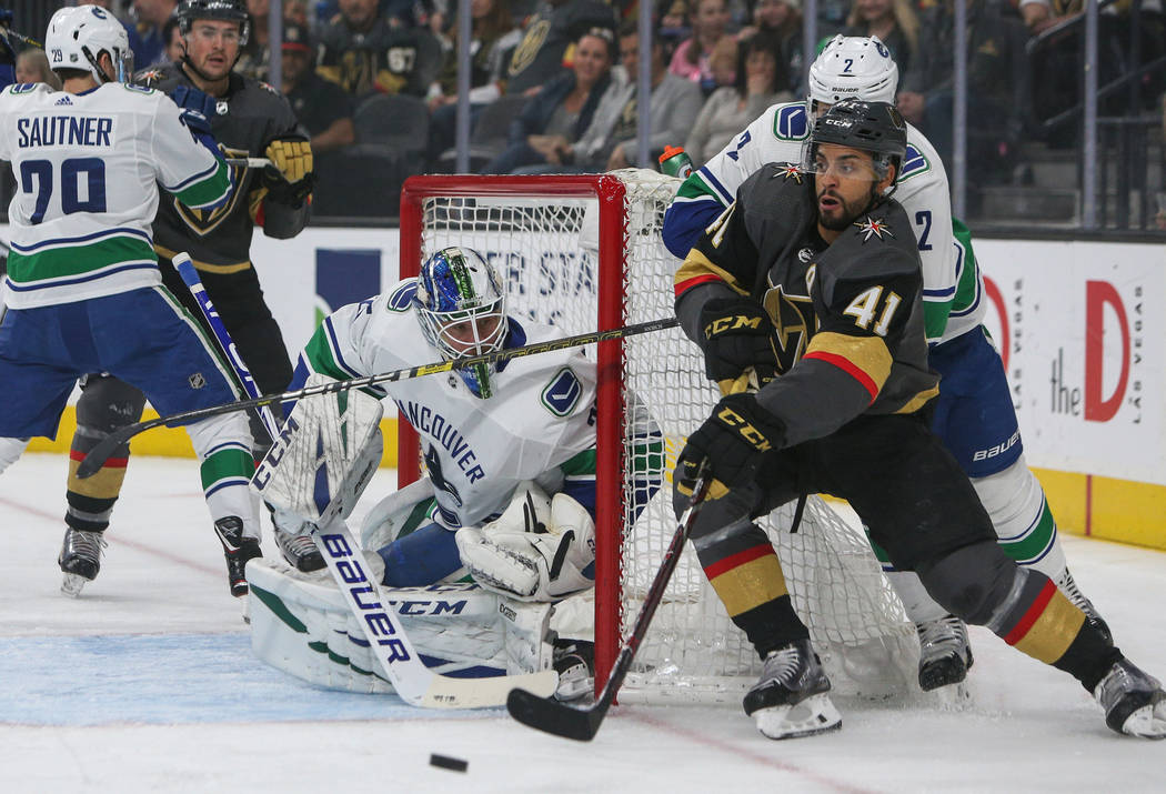 Vegas Golden Knights center Pierre-Edouard Bellemare (41) rounds the net with the puck as Vancouver Canucks defenseman Luke Schenn (2) trails close behind during the first period of an NHL hockey ...
