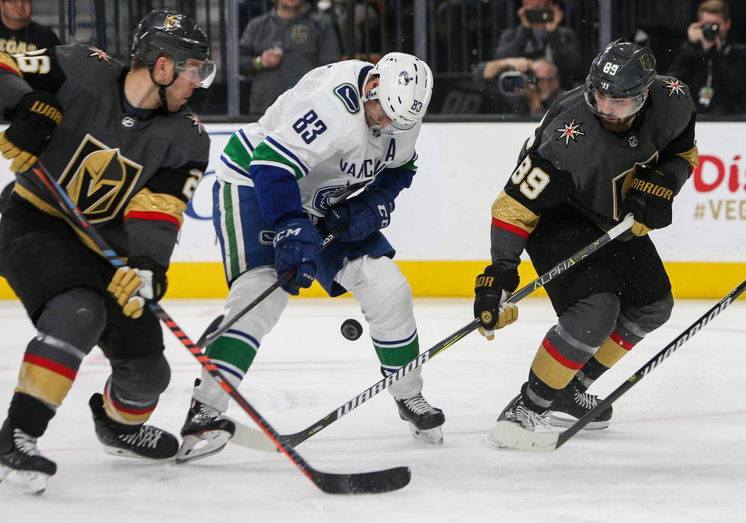 Vancouver Canucks center Jay Beagle (83) looks down at the puck as he is guarded by Vegas Golden Knights center Paul Stastny (26) and Vegas Golden Knights right wing Alex Tuch (89) during the thir ...