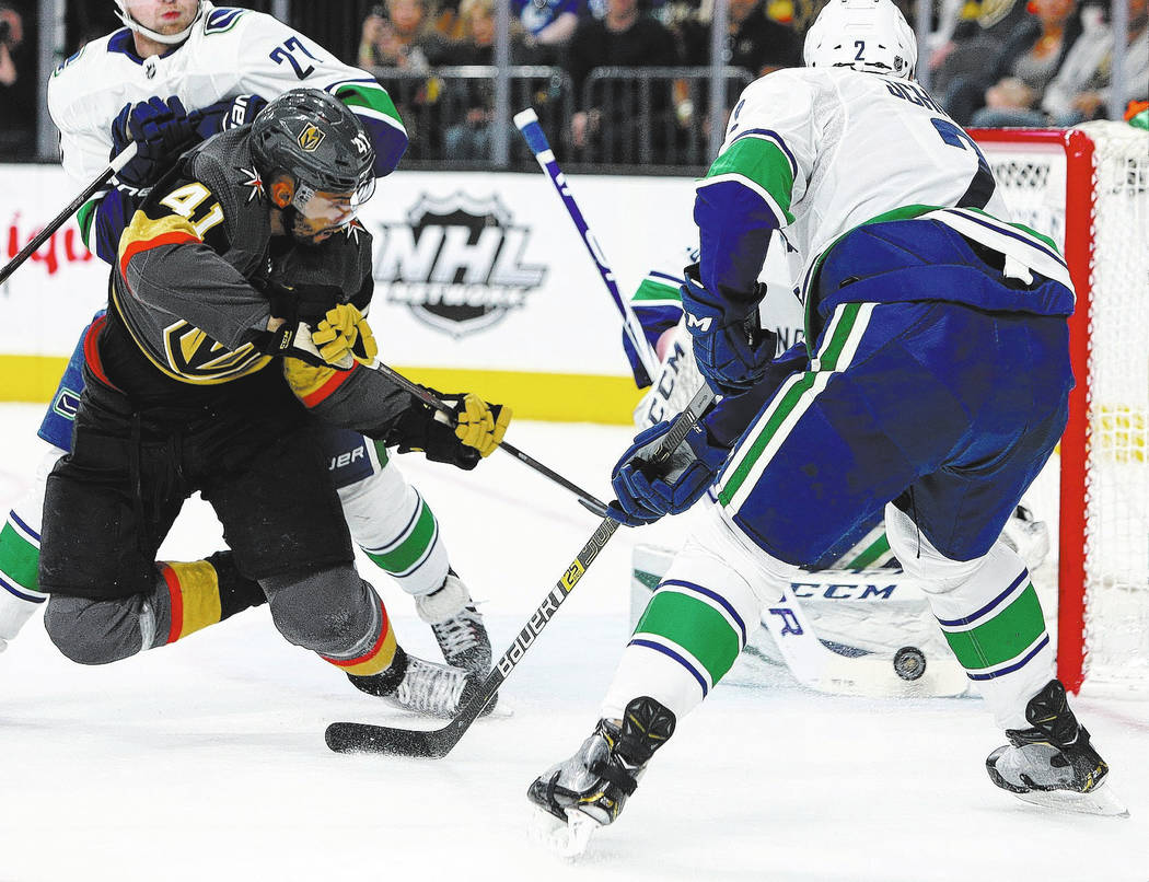 Vegas Golden Knights center Pierre-Edouard Bellemare (41) takes a shot behind his back against Vancouver Canucks goaltender Jacob Markstrom (25) during the first period of an NHL hockey game at T- ...