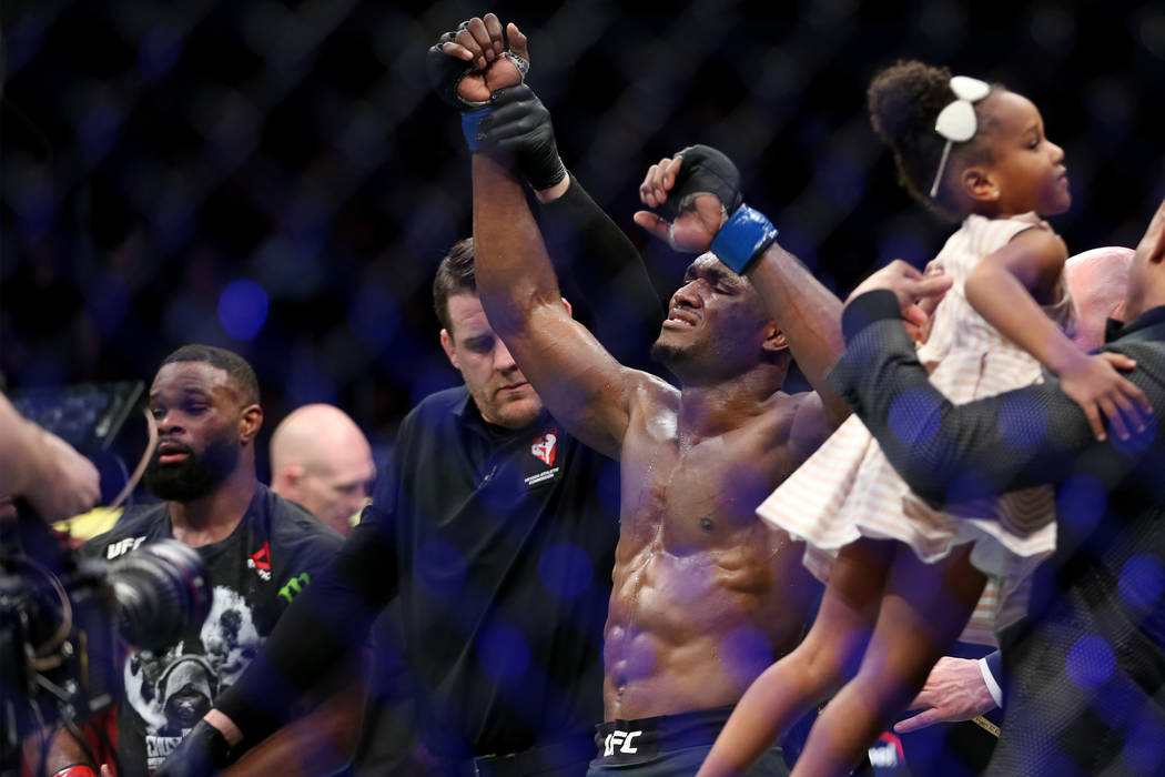 Kamaru Usman, right, raises his hand in victory against Tyron Woodley in the welterweight title bout during UFC 235 at T-Mobile Arena in Las Vegas, Saturday, March 2, 2019. Usman won by unanimous ...