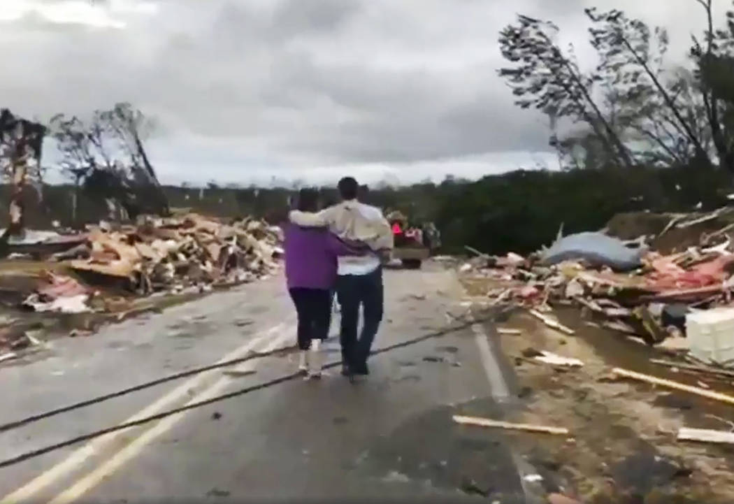People walk amid debris in Lee County, Ala., after what appeared to be a tornado struck in the area Sunday, March 3, 2019. Severe storms destroyed mobile homes, snapped trees and left a trail of d ...