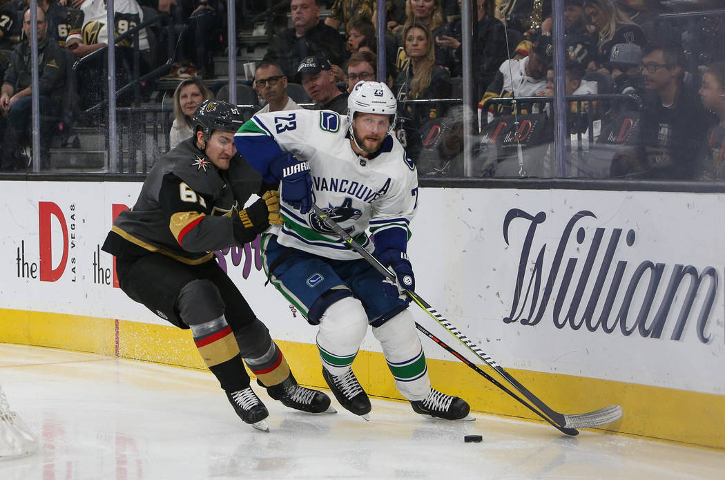 Vancouver Canucks defenseman Alexander Edler (23) looks to pass the puck as Vegas Golden Knights right wing Mark Stone (61) attempts to steal the puck during the third period of an NHL hockey game ...