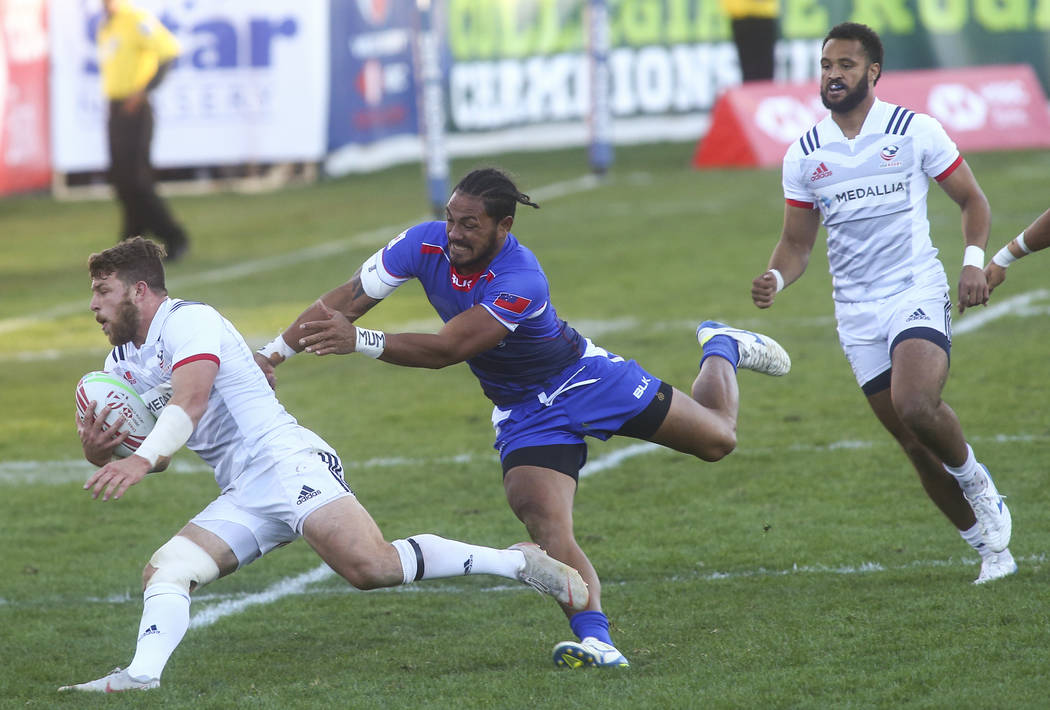 USA's Steve Tomasin, left, runs with the ball as Samoa's Siaosi Asofolau attempts to tackle while competing in the Cup Final during the USA Sevens Rugby Tournament at Sam Boyd Stadium in Las Vegas ...