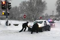 Flagstaff police officers help a motorist push a car stuck in snow in Flagstaff, Ariz., on Feb. 22, 2019. (Jennifer Brown/Flagstaff Police Department via AP)