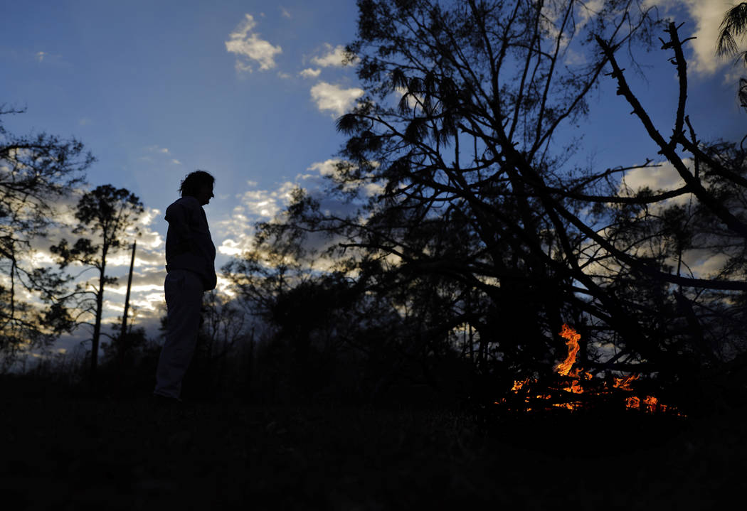 Kathryn Welch burns a pile of branches she cut off the trees that fell around her home from Hurricane Michael in Cottondale, Fla, Tuesday, Jan. 22, 2019. Welch has spent hours everyday clearing he ...