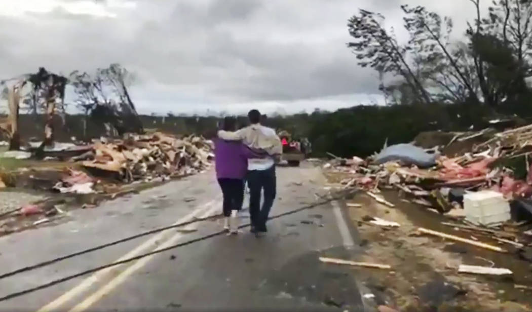 People walk amid debris in Lee County, Ala., after what appeared to be a tornado struck in the area Sunday, March 3, 2019. Severe storms destroyed mobile homes, snapped trees and left a trail of d ...