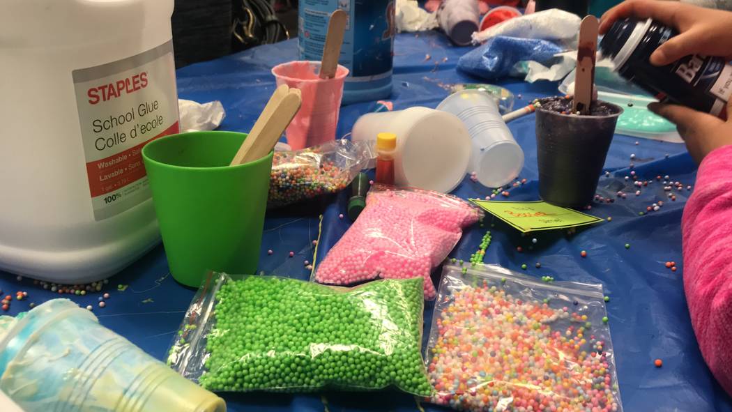 Library volunteers helped children and parents make slime. Glue, foam beads, slime and sticks covered the tables as the children toyed with the decorated goo in their hands. (Mia Sims-Las Vegas Re ...