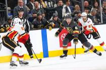 Golden Knights right wing Mark Stone (61) chases after the puck against Calgary Flames defenseman Noah Hanifin (55) and right wing Michael Frolik (67) during the first period of an NHL hockey game ...