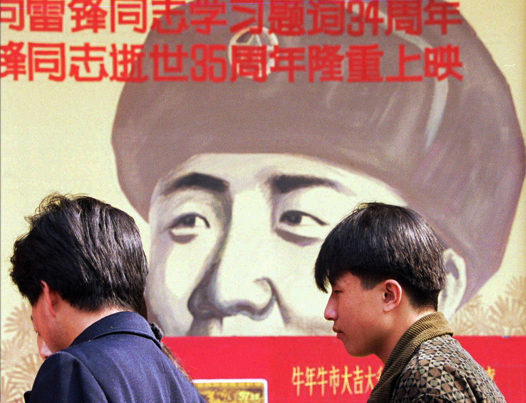 In this March 5, 1997, file photo, Chinese wait outside a movie theater featuring a poster promoting a movie about Lei Feng, a soldier in the 1960's who was promoted to hero and model soldier stat ...