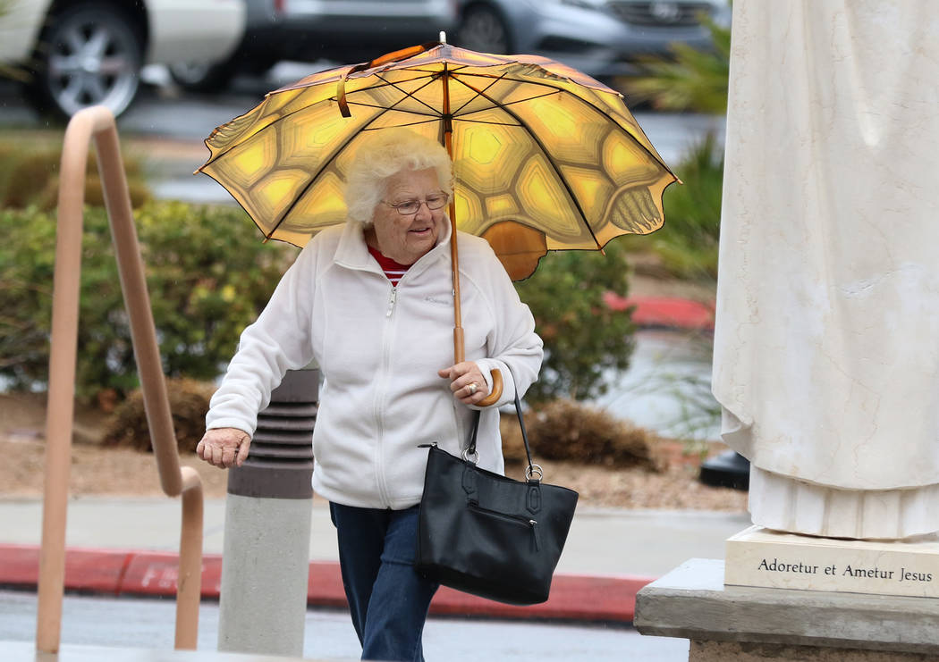 A woman holds an umbrella to protect herself from rain as she heads to St. Viator Catholic Church on Wednesday, March. 6, 2019, in Las Vegas. (Bizuayehu Tesfaye/Las Vegas Review-Journal) @bizutesfaye