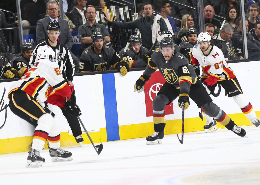 Golden Knights right wing Mark Stone (61) chases after the puck against Calgary Flames defenseman Noah Hanifin (55) and right wing Michael Frolik (67) during the first period of an NHL hockey game ...