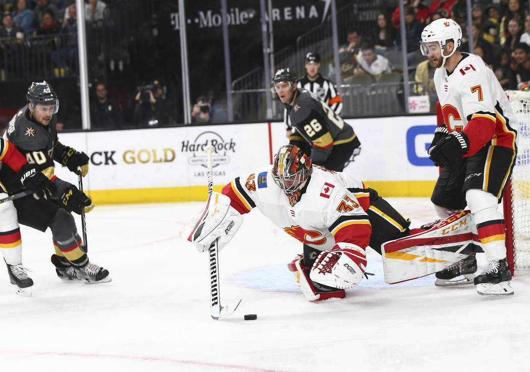 Calgary Flames goaltender David Rittich (33) stops the puck in front of Golden Knights center Ryan Carpenter (40) as Calgary Flames defenseman TJ Brodie (7) looks on during the second period of an ...