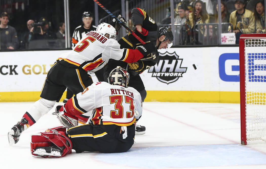 Golden Knights right wing Reilly Smith (19) watches the puck under pressure from Calgary Flames defenseman Mark Giordano (5) as goaltender David Rittich (33) looks on during the second period of a ...