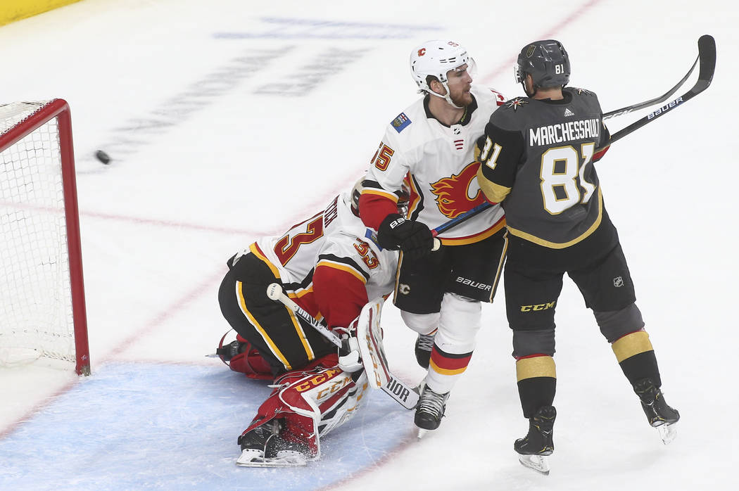 Golden Knights defenseman Deryk Engelland, not pictured, sends the puck past Calgary Flames goaltender David Rittich (33) and defenseman Noah Hanifin (55) as Golden Knights center Jonathan Marches ...