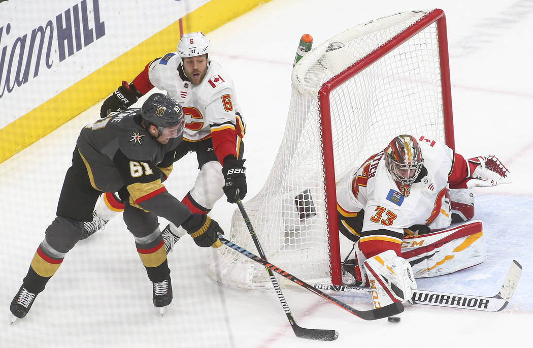 Golden Knights right wing Mark Stone (61) tries to get the puck in against Calgary Flames goaltender David Rittich (33) under pressure from defenseman Dalton Prout (6) during the third period of a ...
