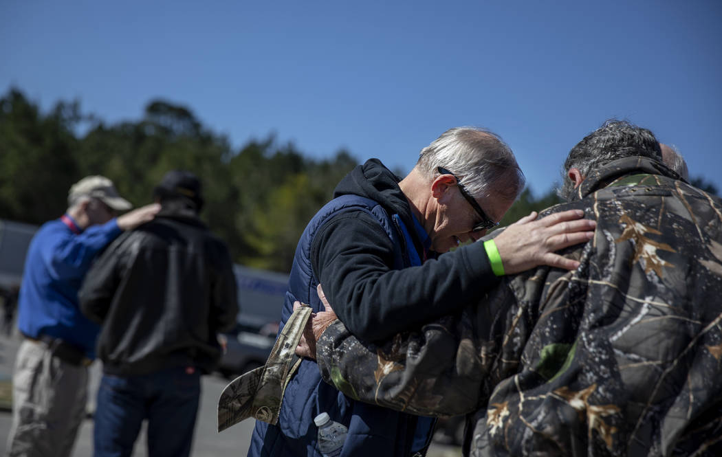 Rand Bowman, center, prays with fellow volunteer, Paul Kelley, outside a donation distribution site in Opelika, Ala., Wednesday, March 6, 2019. (AP Photo/David Goldman)