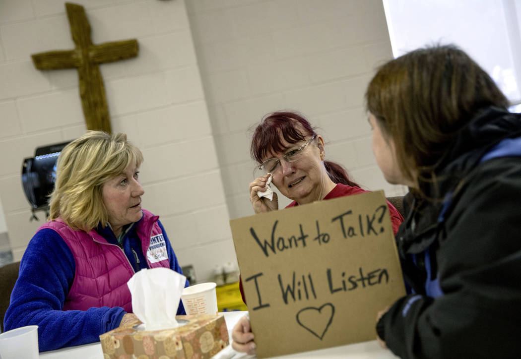 Vivian Martin, center, is comforted by fellow resident, Susan Thompson, left, and grief counselor, Jenny Filush-Glaze, at Providence Baptist Church, while talking about feeling guilty her home was ...