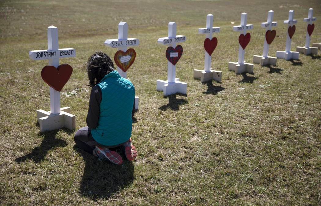 Jessica Taylor prays in front of a cross for Jonathan Bowen, 9, at a makeshift memorial for the victims of a tornado in Beauregard, Ala., Wednesday, March 6, 2019. "I have a son his age," ...