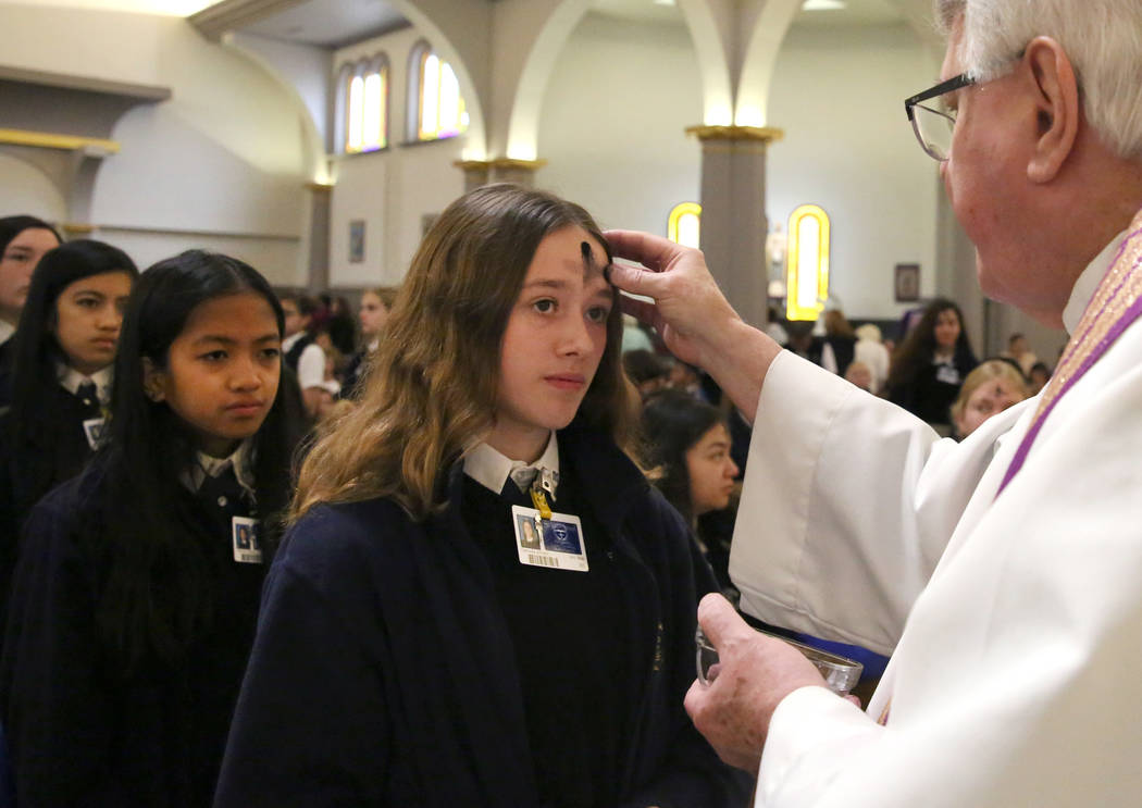 Rev. Larry Lentz applies ashes on St. Viator Parish School student Gabriella Johnson's forehead at St. Viator Catholic Church during Ash Wednesday on Wednesday, March. 6, 2019, in Las Vegas. Bizua ...