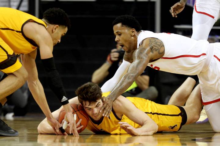 Wyoming's Hunter Thompson, center, Justin James, left, and New Mexico's Corey Henson reach for a loose ball during the first half of an NCAA college basketball game in the Mountain West Conference ...