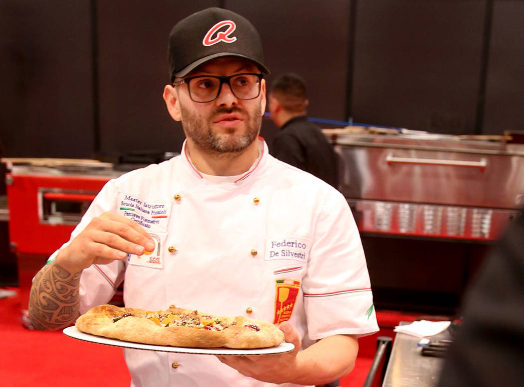 Federico De Silvestri of Verona, Italy, presents his pizza to the judges while competing in the finals for the non-traditional pizza category during the International Pizza Challenge at the Intern ...