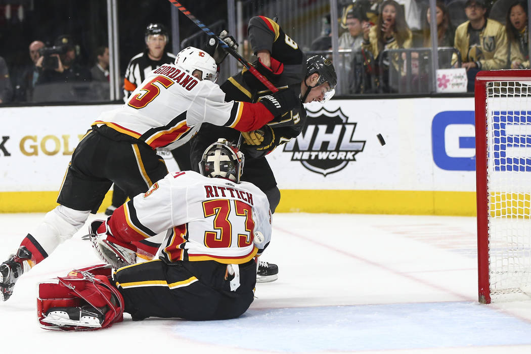 Golden Knights right wing Reilly Smith (19) watches the puck under pressure from Calgary Flames defenseman Mark Giordano (5) as goaltender David Rittich (33) looks on during the second period of a ...