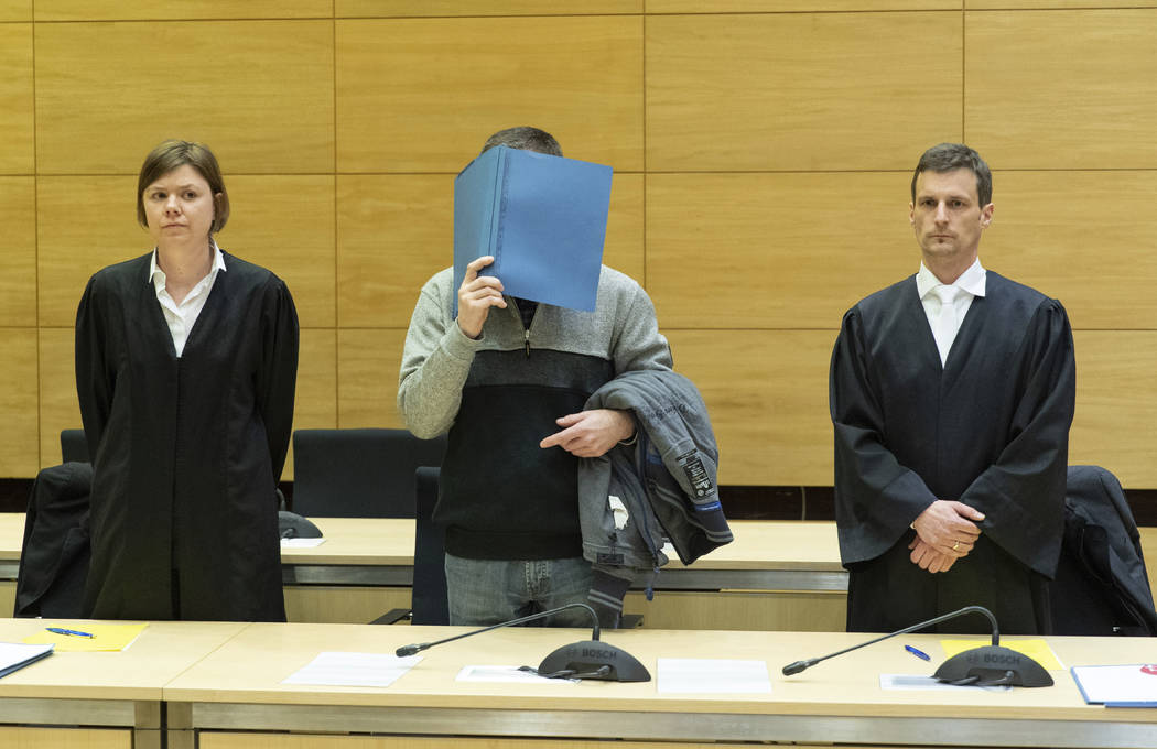 A 57-year old defendant hides his face at the courtroom in Bielefeld, Germany, Thursday, March 7, 2019. A judge in Germany has found the man guilty of poisoning his co-workers' sandwiches with mer ...