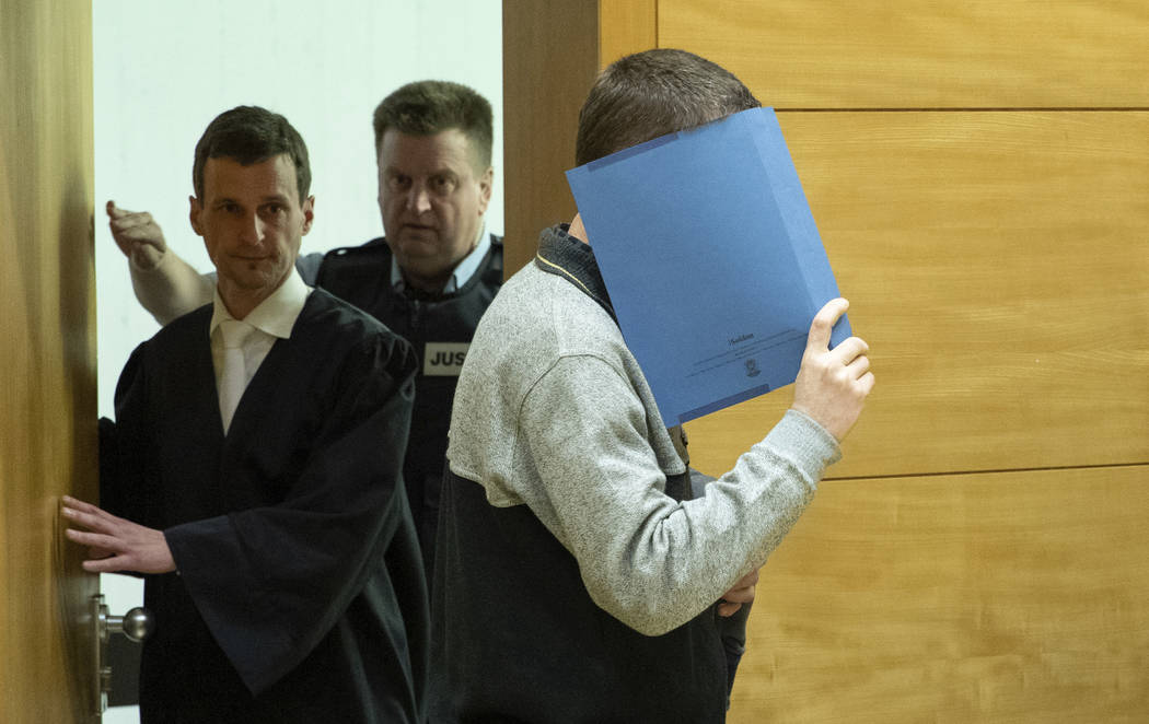 A 57-year old defendant hides his face at the courtroom in Bielefeld, Germany, Thursday, March 7, 2019. A judge in Germany has found the man guilty of poisoning his co-workers' sandwiches with mer ...