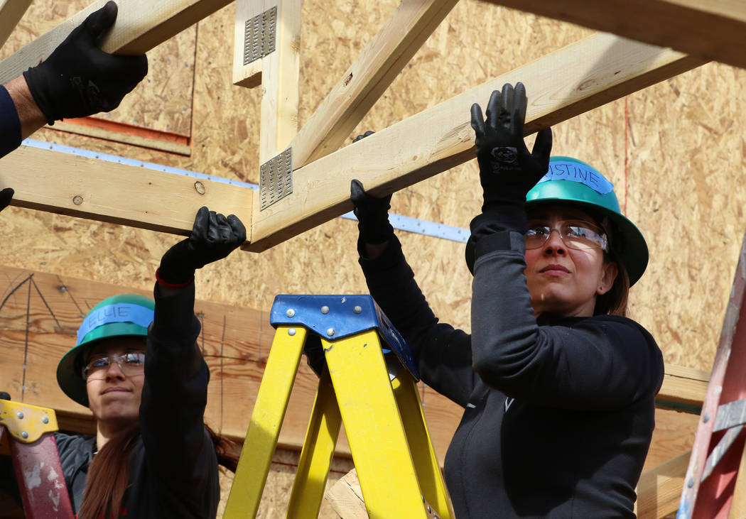 Ellie Lukova, left, and Christine Monjer of the Las Vegas Aces help raise roof trusses as they volunteer with the construction of Habitat for Humanity Las Vegas’ 112th home in celebration of Int ...