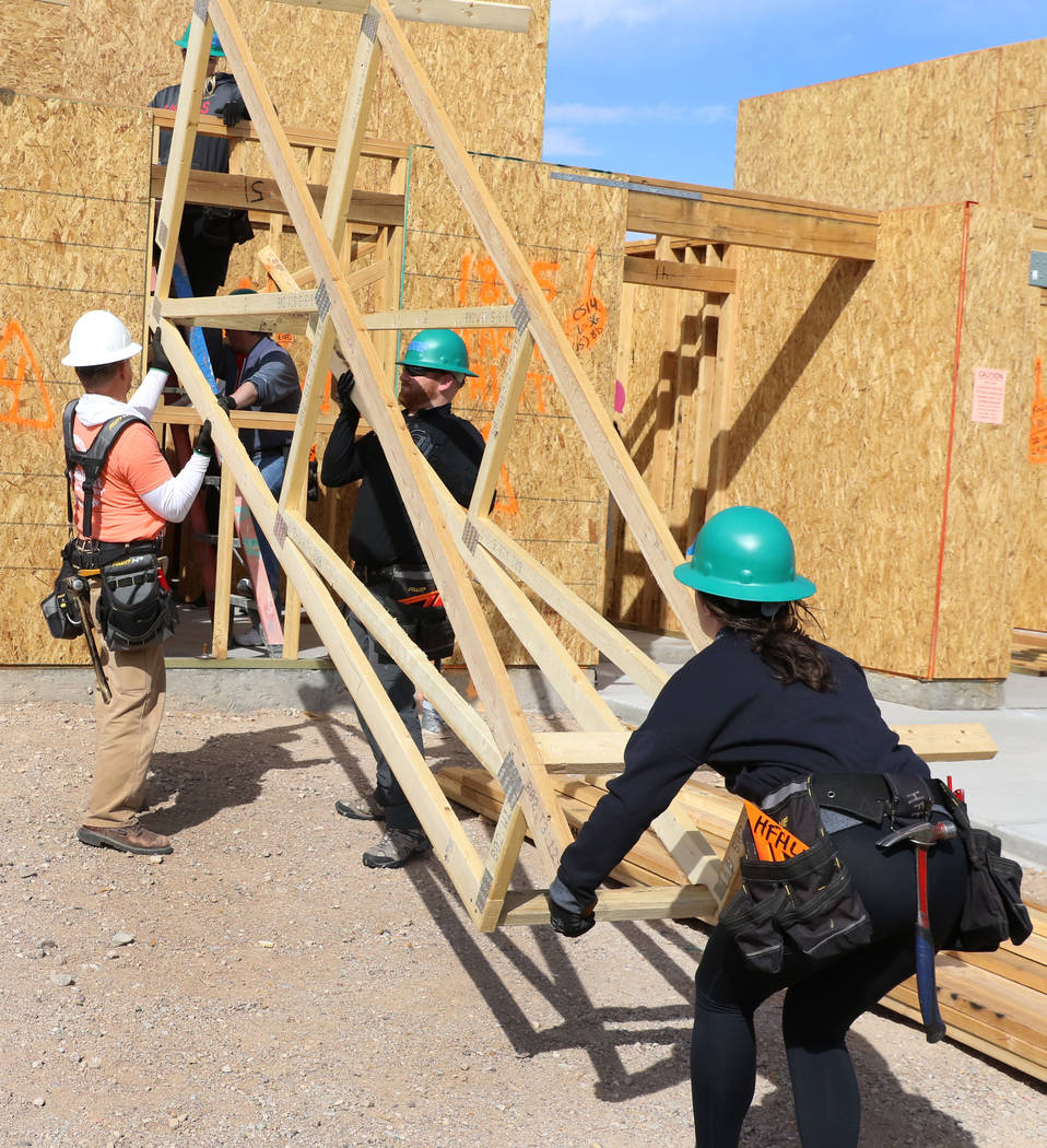 John Maxwell, left, site supervisor for Habitat for Humanity Las Vegas, Blake Broaddus, center, and Taylor Janison of the Las Vegas Aces help raise roof trusses as they volunteer with the construc ...