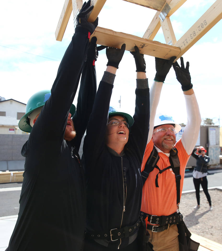 Blake Broaddus, left, Taylor Janison, center, of the Las Vegas Aces, and John Maxwell, right, site supervisor for Habitat for Humanity, raise roof trusses as they volunteer with the construction o ...