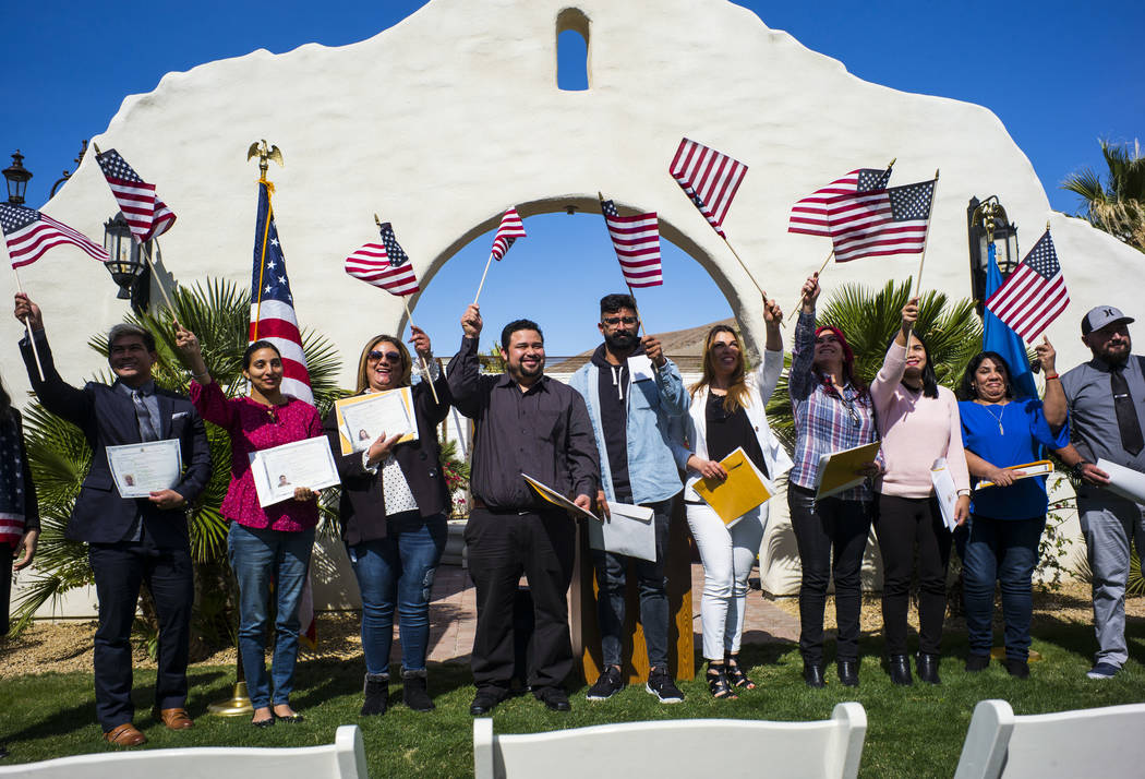 Attendees including Mandeep Kaur of Bakersfield, Calif., second from the left, and Raul Vargas, originally from Guatemala, the fourth from the left, pose for photographs while waving their flags a ...