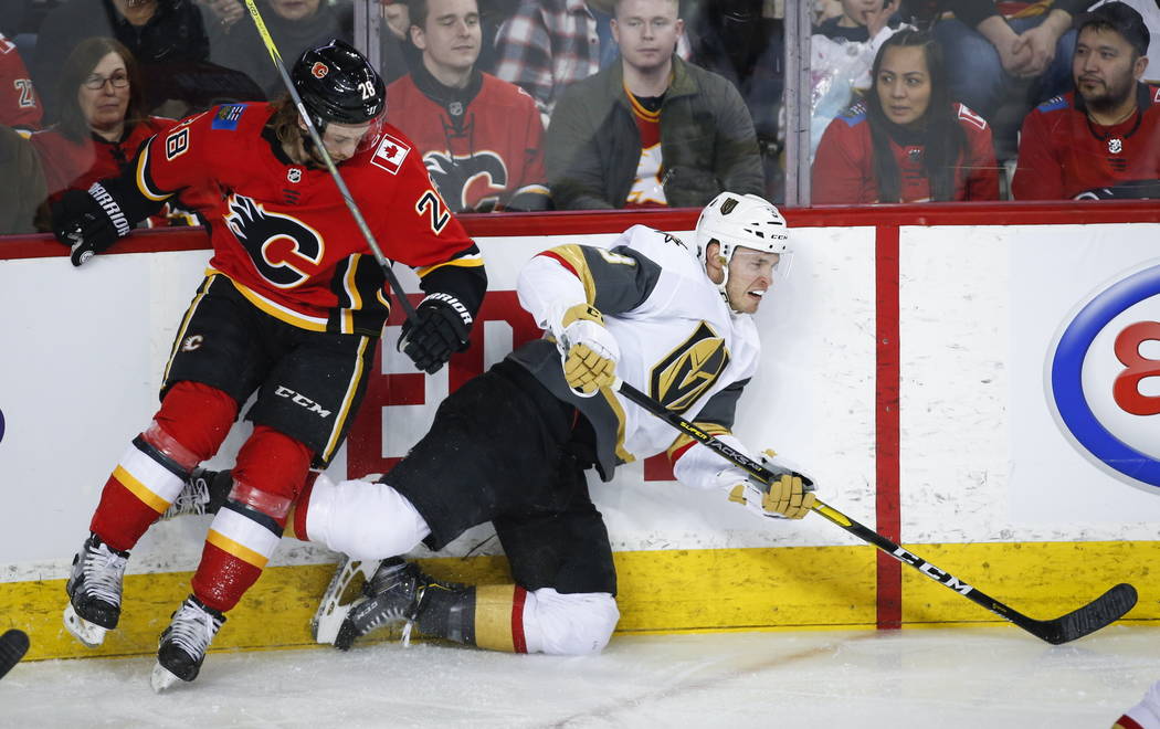 Vegas Golden Knights' Brayden McNabb, right, is checked by Calgary Flames' Elias Lindholm, of Sweden, during first period NHL hockey action in Calgary, Alberta, Sunday, March 10, 2019. (Jeff McInt ...