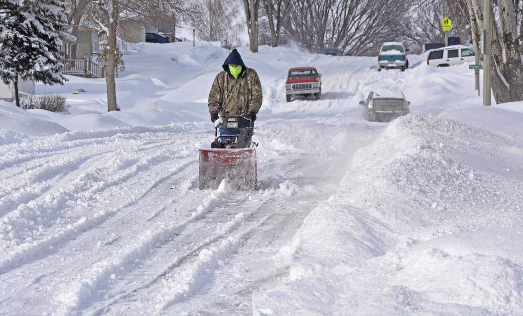 Randy Ohlhauser clears snow from the street next to his home on Saturday, March 9, 2019, in Bismarck, N.D., to make room for evening guests to park their vehicles. "We're having a pinochle ca ...