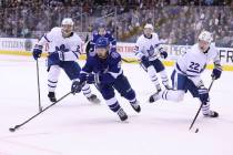 Tampa Bay Lightning center Tyler Johnson (9) controls the puck by Toronto Maple Leafs defensemen Nikita Zaitsev (22) and Ron Hainsey (2) during second-period NHL hockey game action in Toronto, Mon ...