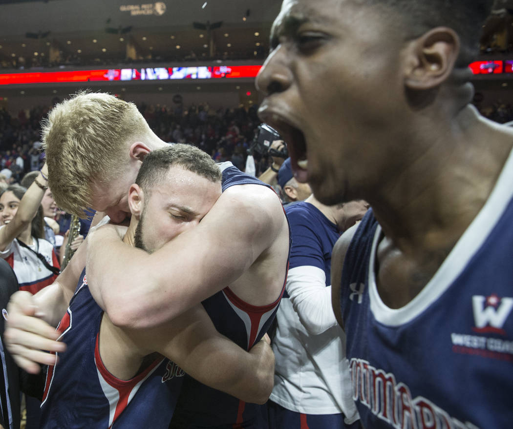 St. Mary's junior guard Jordan Ford, left, gets a big hug from teammate Matthias Tass while sophomore forward Malik Fitts, right, celebrates after the Gaels upset Gonzaga 60-47 to win the West Coa ...