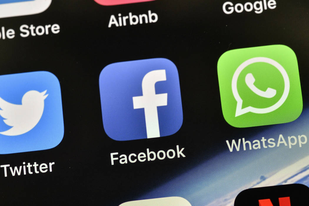 The icons of Facebook and WhatsApp are pictured on an iPhone. (AP Photo/Martin Meissner)