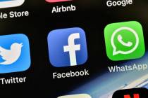 The icons of Facebook and WhatsApp are pictured on an iPhone. (AP Photo/Martin Meissner)