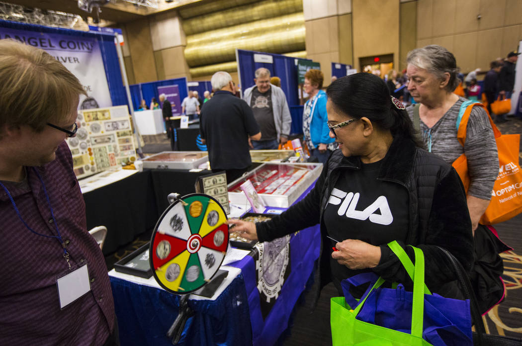 Catalina Perito of Las Vegas, right, spins a wheel for a giveaway as Christopher Shands of Archangel Coins looks on during the fifth annual AgeWell Expo at the Rio Convention Center in Las Vegas o ...