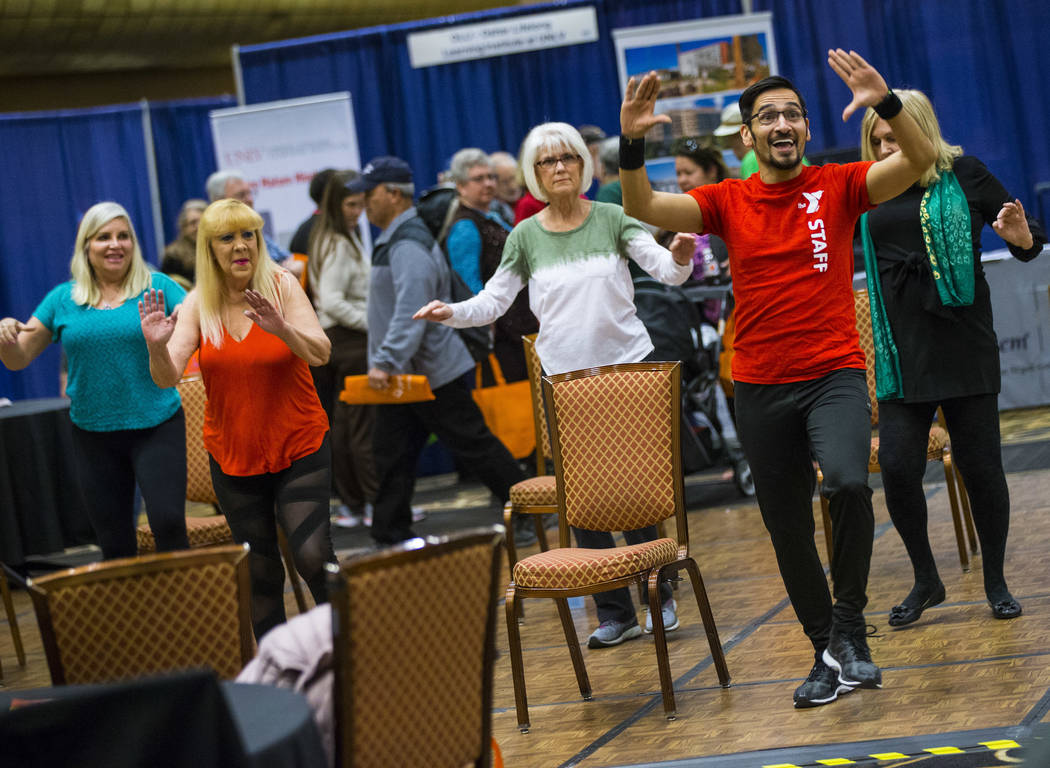 Jonathan Jimenez, health & wellness coordinator at the Bill & Lillie Heinrich YMCA, leads attendees in a Silver Sneakers exercise during the fifth annual AgeWell Expo at the Rio Convention ...