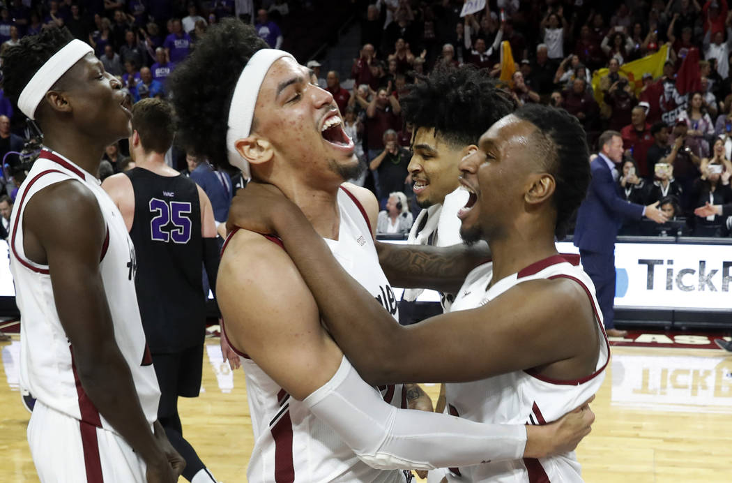New Mexico State forward Eli Chuha, center, and teammate C.J. Bobbitt, right, celebrate the team's 89-57 win over Grand Canyon in an NCAA college basketball game for the Western Athletic Conferenc ...