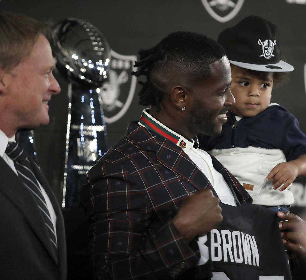 Oakland Raiders wide receiver Antonio Brown, center, holds his son Apollo beside coach Jon Gruden, left, after an NFL news conference Wednesday, March 13, 2019, in Alameda, Calif. (AP Photo/Ben Ma ...