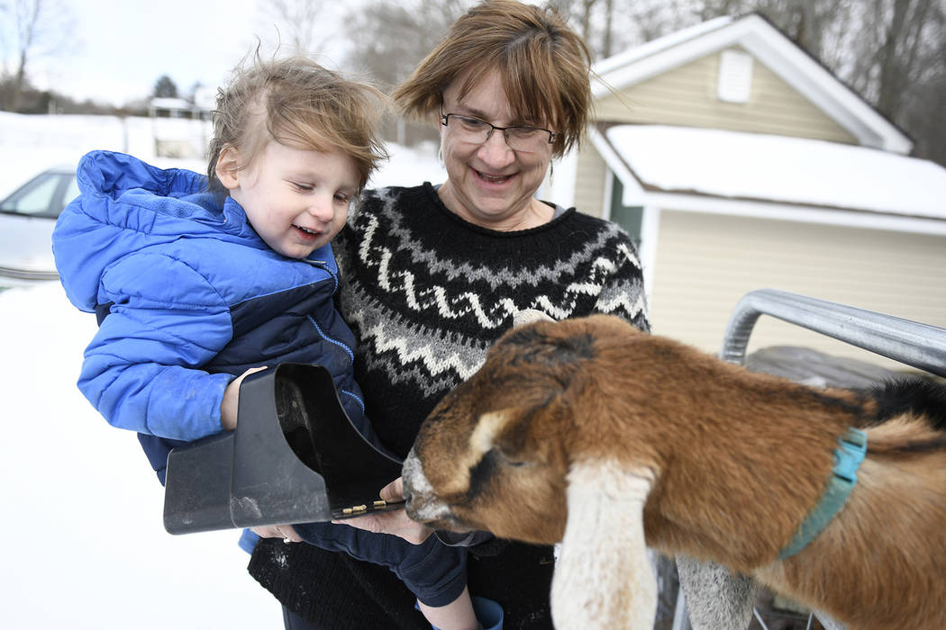 Sally Stanton, right, holds her grandson Murphy Drzewianowski as he feeds Lincoln the goat in Fair Haven, Vt. (/The Rutland Herald via AP)