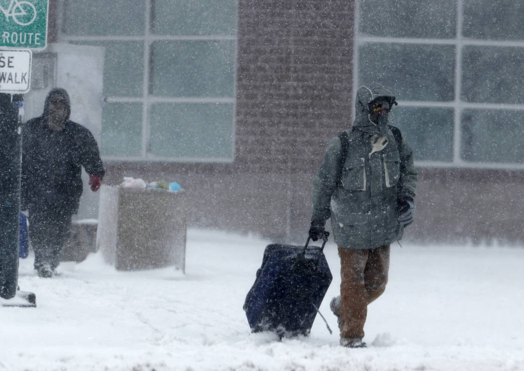 A traveller drags a suitcase as a late winter storm packing hurricane-force winds and snow sweeps over the intermountain West Wednesday, March 13, 2019, in Denver. (AP Photo/David Zalubowski)